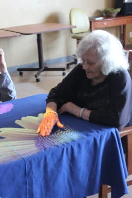 elderly woman sitting at a table doing arts and crafts