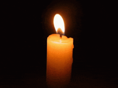 single candle burning behind a black background